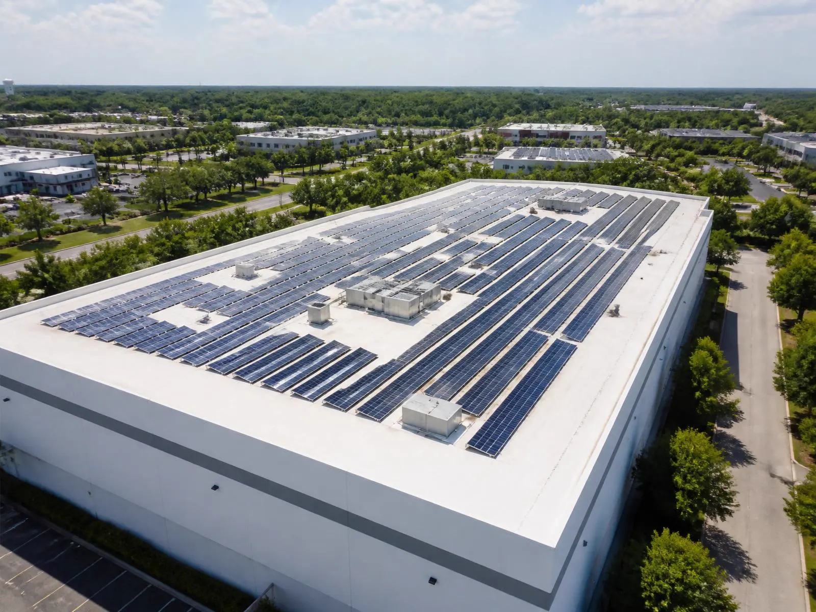 Plochá strecha firemnej budovy s radmi fotovoltaických panelov z výšky